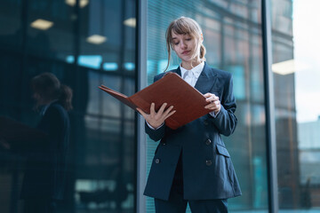 Professional woman reviewing documents outdoors in a modern urban setting during daylight hours