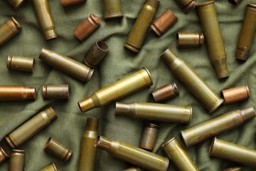 Many used rifle cartridges on military camo green fabric background