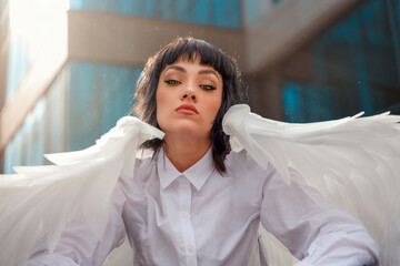 Angelic figure with white wings confidently poses in the city, radiating beauty and innocence
