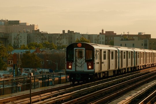 A 7 train travels through Queens, New York, illuminated by the setting sun.