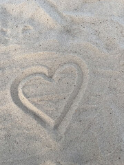 heart symbol drawn on white sand on the beach. Concept of love and seaside vacation 