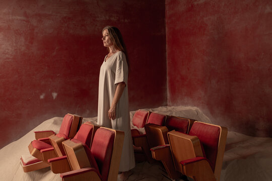 Woman Standing Thoughtfully Among Vintage Theater Seats