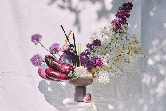 Composition in a vase with vegetables and flowers on a pedestal