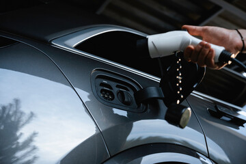 The man connects the charging to the electric car