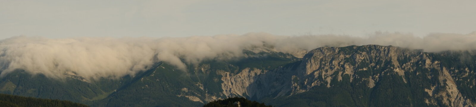 Panorama of sunrise in mountains with clouds.