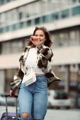 Charming Woman Strolls Through the City in a Stylish Plaid Shirt, Blue Pants, and Sunglasses.