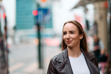 Charming Woman Strolls Through City Streets Wearing a Fashionable Leather Jacket.