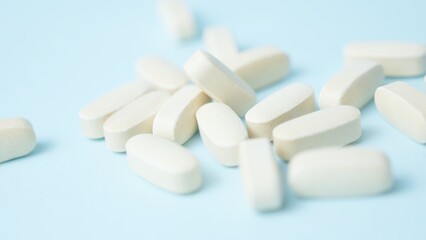 A bunch of white pills tablets on light blue background,. High quality photo
