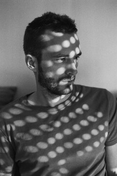 Black and white portrait of a man with shadows and sun on his face