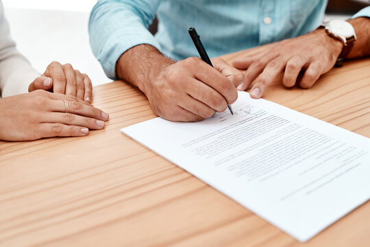 Fototapeta Person, hands and writing with signature on contract for insurance, application or legal agreement on wooden table. Closeup, people or signing with paper for deal, policy or employment form on desk