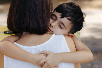 Boy hugging mum with eyes closed in heartfelt embrace