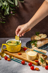Chef adding croutons to creamy green pea soup with dill and baguette