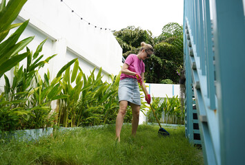 A woman raking the lawn at the backyard of her house 