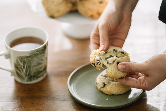 Hands breaking an oat cookie in half, two more behind