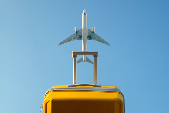 Yellow suitcase with luggage in the background of a passing aircraft 