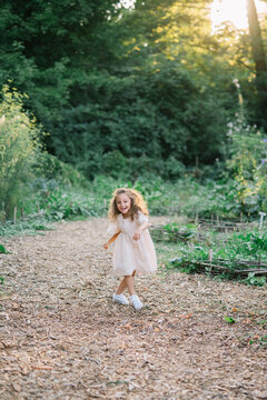 Smiling child runs through path in lush green garden