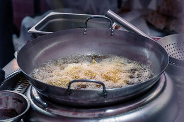 Boiling oil in a wok pan close up. Cooking in an Asian restaurant. Traditional deep steel cookware. Selective focus