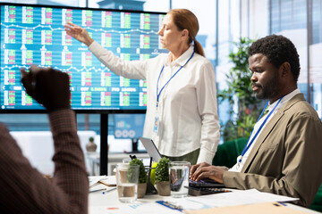 General manager making a presentation with infographics and sales numbers on interactive board, showing the organizational progress to the staff. Employees reviewing analytics plans.