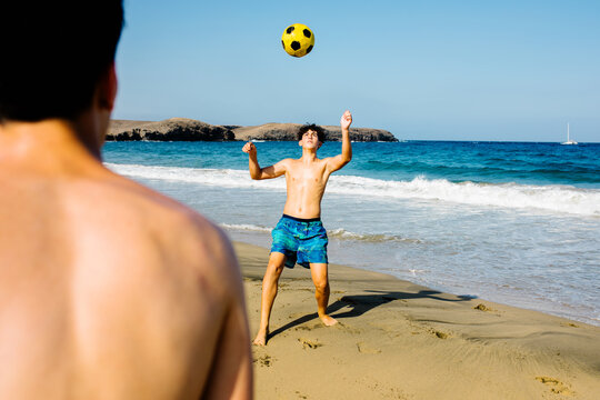 Teenage brothers enjoy a sunny day  playing freestyle at the beach