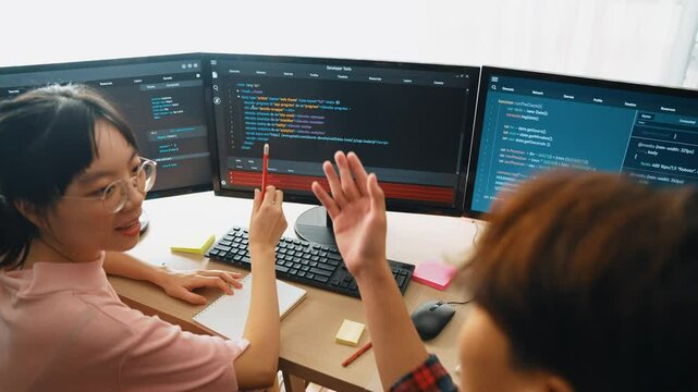 Slow motion back end software developer engineer for computer programming working together on debugging writing computing code, solving complex algorithms display on monitor in office. Burgeoning