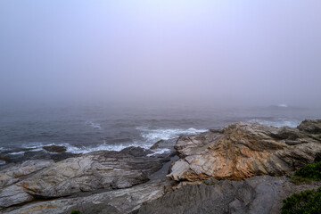 Fog rolls in onto The beautiful rocky coast of the Atlantic Ocean in Newport Rhode Island