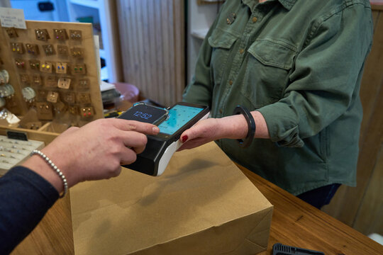 Customer making a contactless payment at a local shop's checkout
