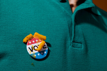 vote badge with remains of mac and cheese on his polo shirt