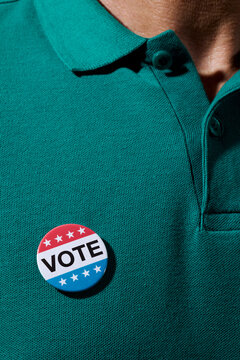 man wearing a vote badge on his green polo shirt