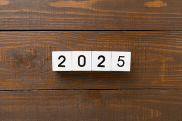 Cubes with 2025 on wooden background, top view