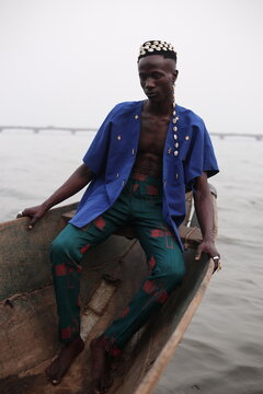  model wearing a hat filled with cowries shells sitting in a boat