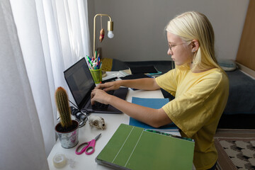 Teen girl working on laptop at home
