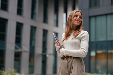 A Confident Young Woman with a Laptop Posing in a Modern Urban Environment Setting