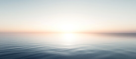 Fototapeta premium A serene seascape with a calm ocean and a hazy sunset.