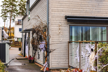 Halloween decorations on house wall with skeleton, ghostly figures, cobwebs, and spooky branches...