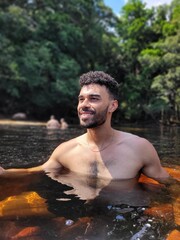 Young Man Posing Near a Waterfall in a Scenic Natural Setting with Trees and Fresh Air