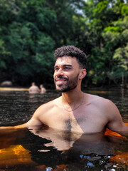 Young Man Posing Near a Waterfall in a Scenic Natural Setting with Trees and Fresh Air