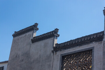 Carved windows on the gray walls of ancient houses of Huizhou architecture
