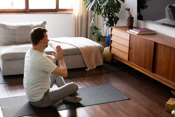 senior man practicing yoga on mat at home, focusing on relaxation and mindfulness