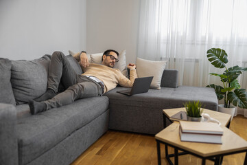 Man Relaxing Casually On Couch With Laptop At Home