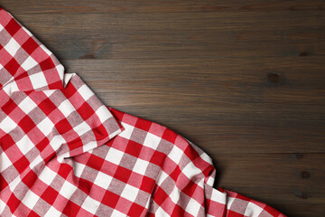 Obraz premium Crumpled tablecloth with checkered pattern on wooden table, top view. Space for text