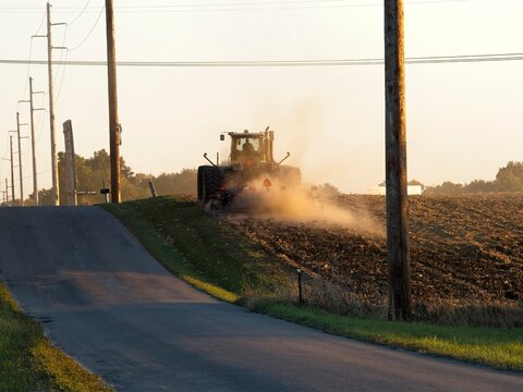 Farmer disking corn field with farm implements on a late fall afternoon