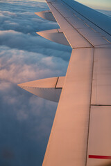 View from airplane window of wing over clouds during flight journey.