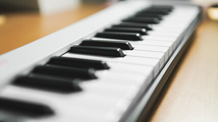 Closeups of a piano, midi controller, or keyboard on a wooden table. Home studio or music equipment concept.