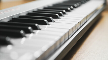 Closeups of a piano, midi controller, or keyboard on a wooden table. Home studio or music equipment concept.
