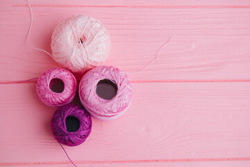 Beautifully arranged yarn balls in pink shades and lace ribbon, ideal for textile, knitting, and crafting themes.