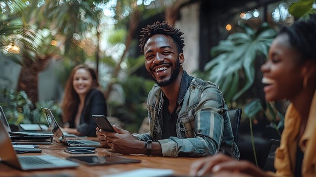 A team of diverse professionals gathered around a table in a modern office using laptops tablets