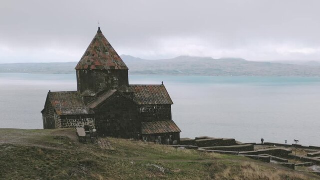 Armenian visitor man person by Sevanavank monastic complex with Lake Sevan panorama in Gegharkunik Province of Armenia. Concept religion in armenian culture. Search purpose answers human concept.