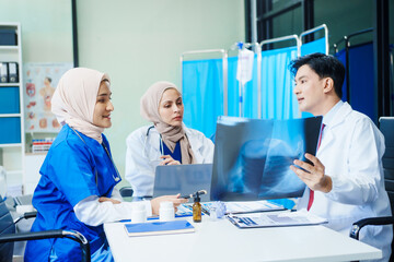 Obraz premium Two Muslim female doctors meet with an Asian male doctor to discuss an X-ray, blood vessel samples, and a medicine bottle, collaborating on diagnostic and treatment plans in a hospital setting