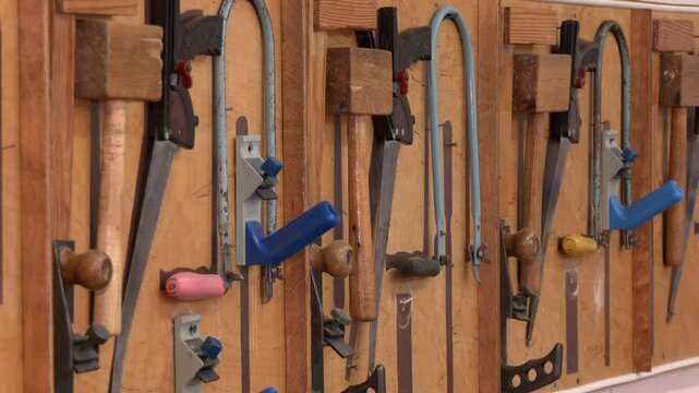 Many different old tools hanging on a barn wall.  Collection of vintage carpentry tools on an old workbench: woodworking, craftsmanship and handwork concept.