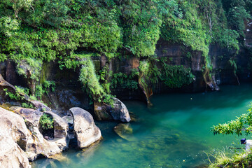Aginma wari in meghalaya india. Lush green cliffs with dense vegetation overhanging a clear emerald...